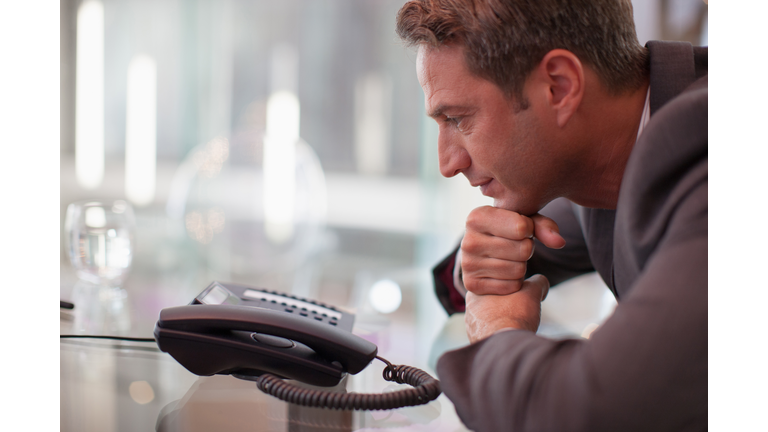 Businessman staring at telephone waiting for it to ring