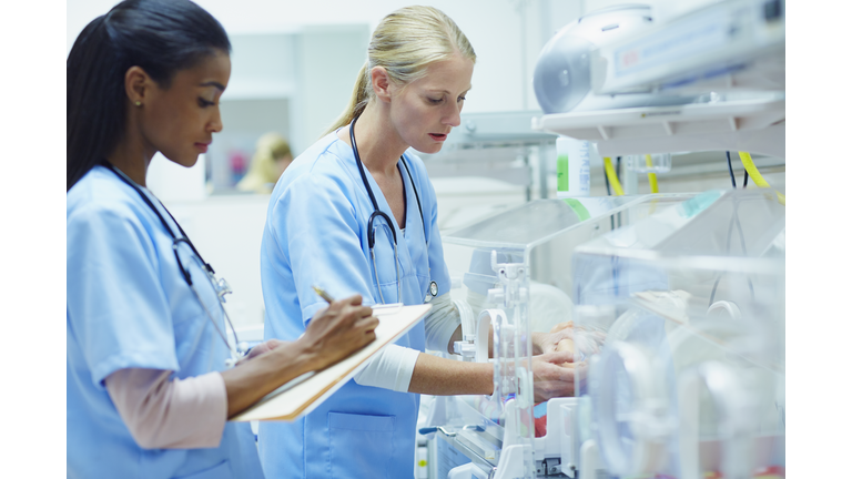 Nurses monitoring baby in incubator