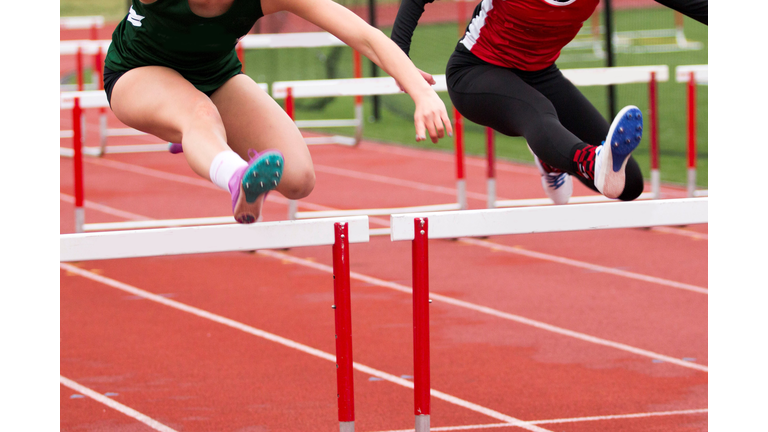 Female Athletes Hurdling On Sports Track