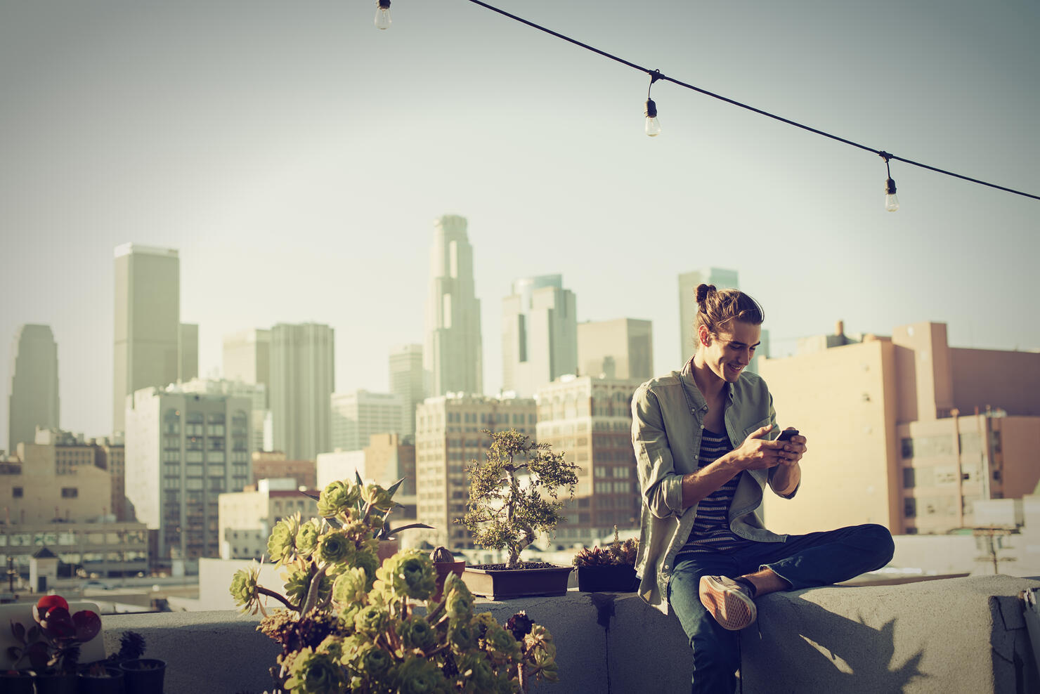 Young man checking his smartphone on urban rooftop