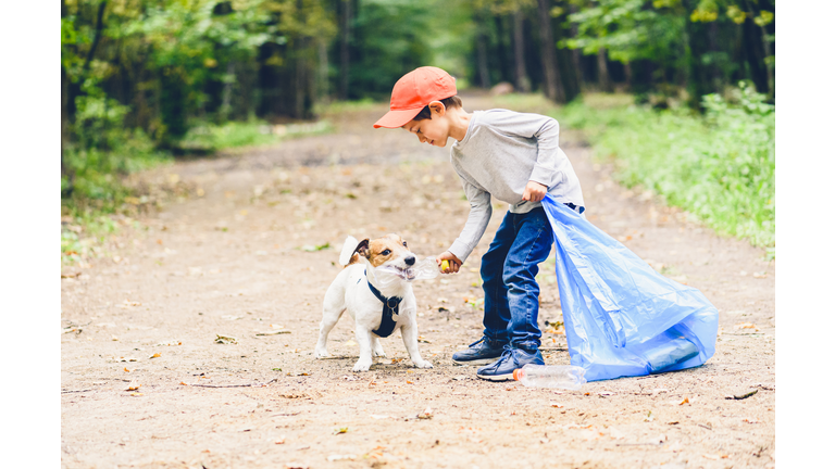 Earth day concept with kid and dog cleaning park gathering plastic bottles