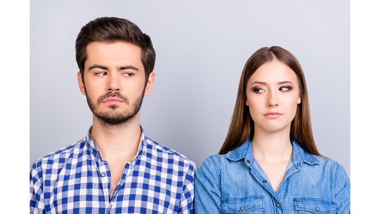 Mistrust and cheat problems. Annoyed couple is ignoring each other, but spy each other secretly, they stand on pure background in casual shirts