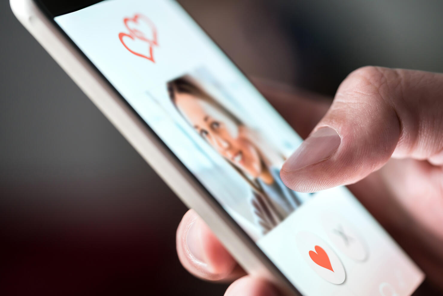 Online dating app in smartphone. Man looking at photo of beautiful woman. Person swiping and liking profiles on relationship site or application. Single guy searching for love partner.
