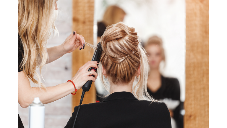 business woman lady boss in beauty salon making hairdress and looking to the mirror