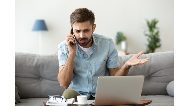 Angry man talking on phone disputing over computer laptop problem