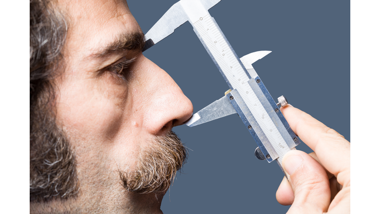 Close Up Portrait Of Adult Man Measuring His Nose