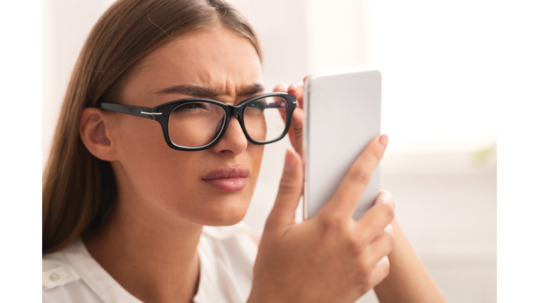 Girl Looking At Cellphone Through Eyeglasses Having Vision Problem Indoor