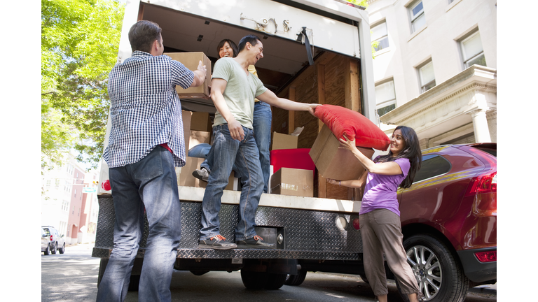 Young Adults moving stuff out of moving truck
