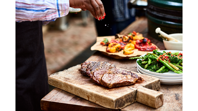 Woman sprinkling salt on freshly cooked steak