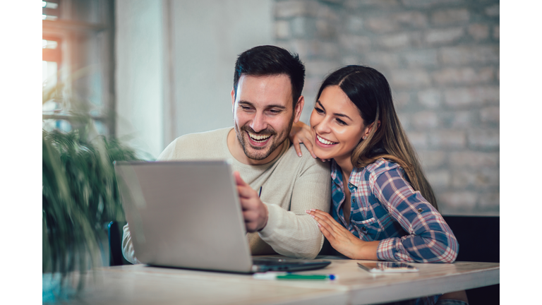 Young Couple Using Laptop On Desk At Home