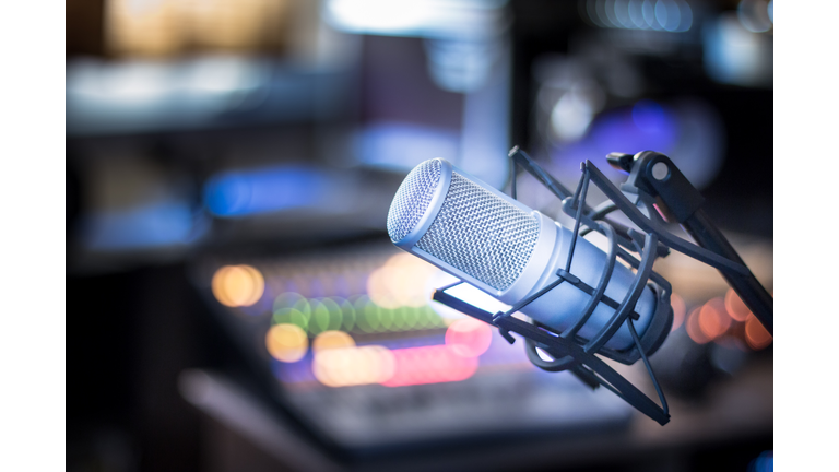 Microphone in a professional recording or radio studio, equipment in the blurry background