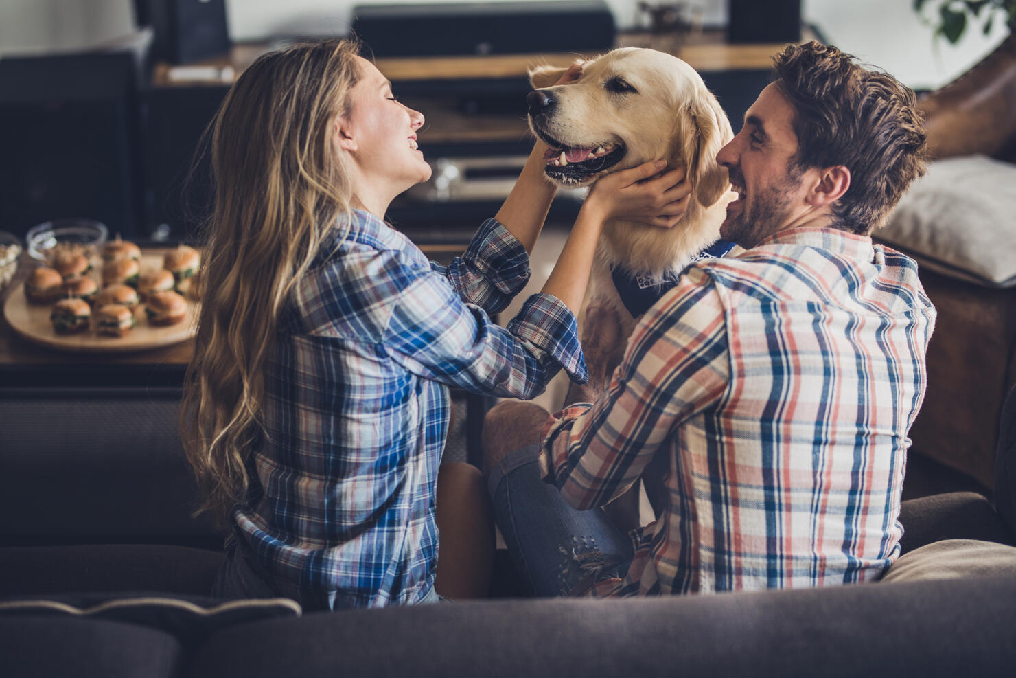 Happy couple enjoying with their golden retriever in the living room.