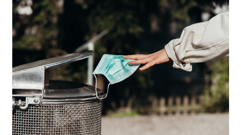 person throws a protective mask into the trash can - 
end of covid-19 corona crisis concept picture