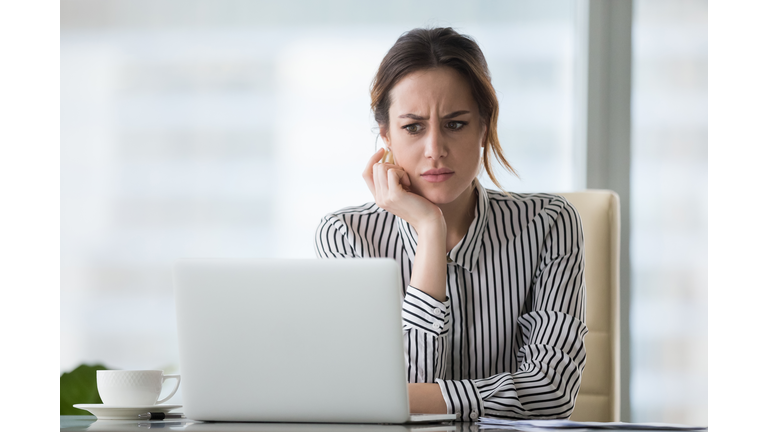 Confused businesswoman annoyed by online problem looking at laptop