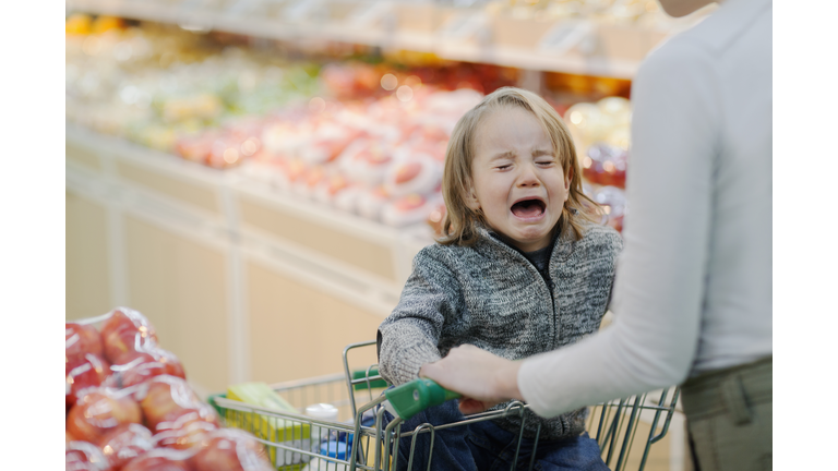 Child crying in shopping cart in supermarket