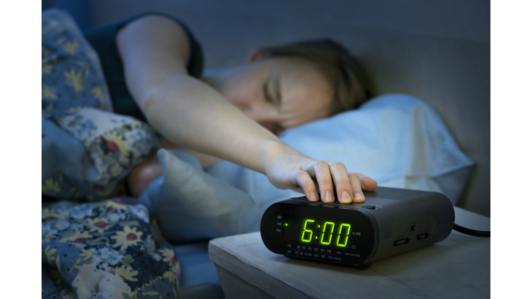 Woman waking up early with alarm clock