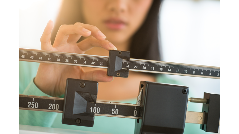 Midsection Of Woman Adjusting Weight Scale