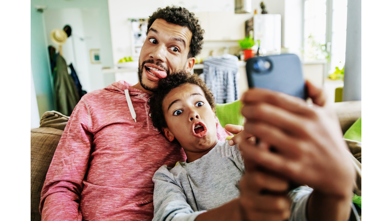 Father And Son Pulling Silly Faces While Taking Selfie Together