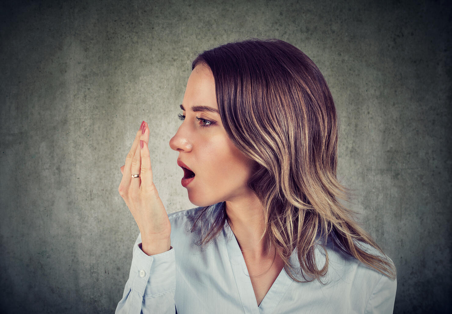 Woman checking her breath with hand.