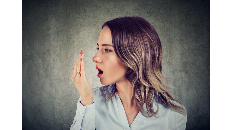 Woman checking her breath with hand.