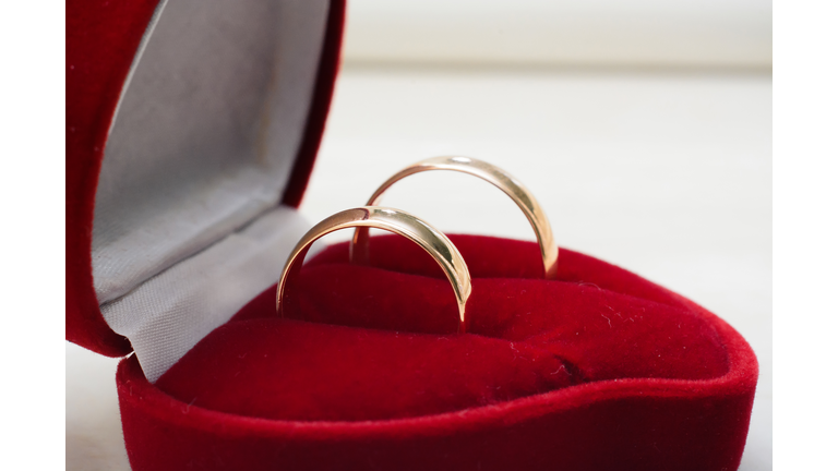 pair of gold wedding rings lie in a red box close-up