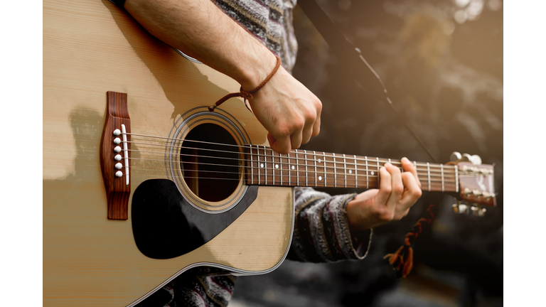 Young musician playing acoustic guitar close up