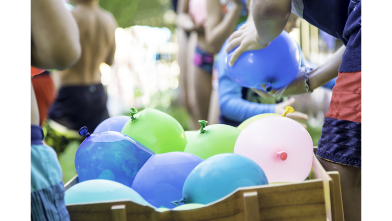 Kids Playing Water Balloons Battle in Summer