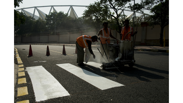 Indian workers paint a zebra crossing on