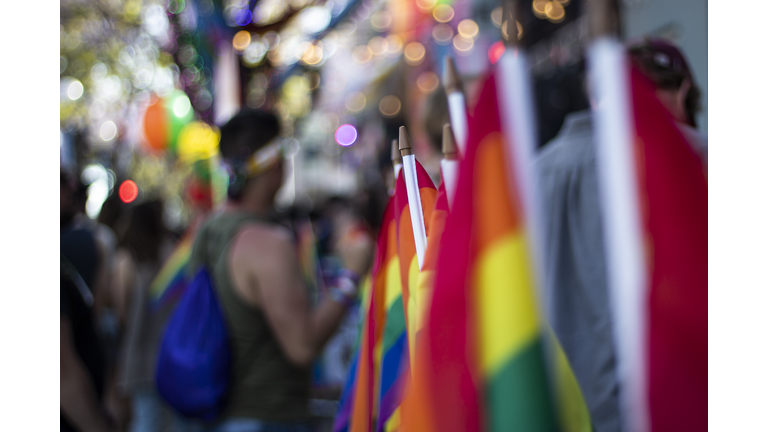 Gay rainbow flag at gay pride parade with blurred participants in the background