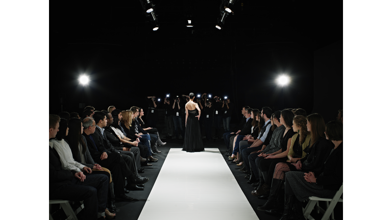 Model in gown at end of catwalk posing