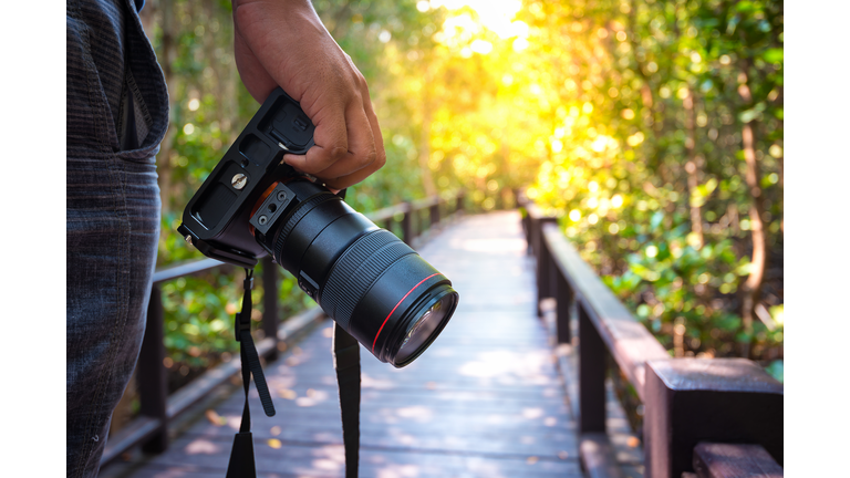 Man holding his camera on walkway during his travel