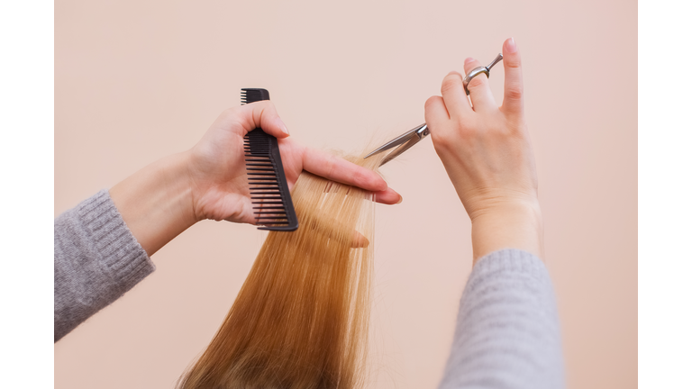 hairdresser does a haircut with scissors of hair to a young girl