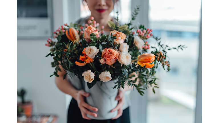 Shot of an unrecognisable woman covering her face with flowers in living room