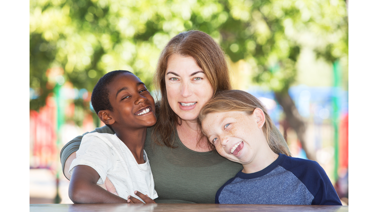 Joyful single parent with sons at park table