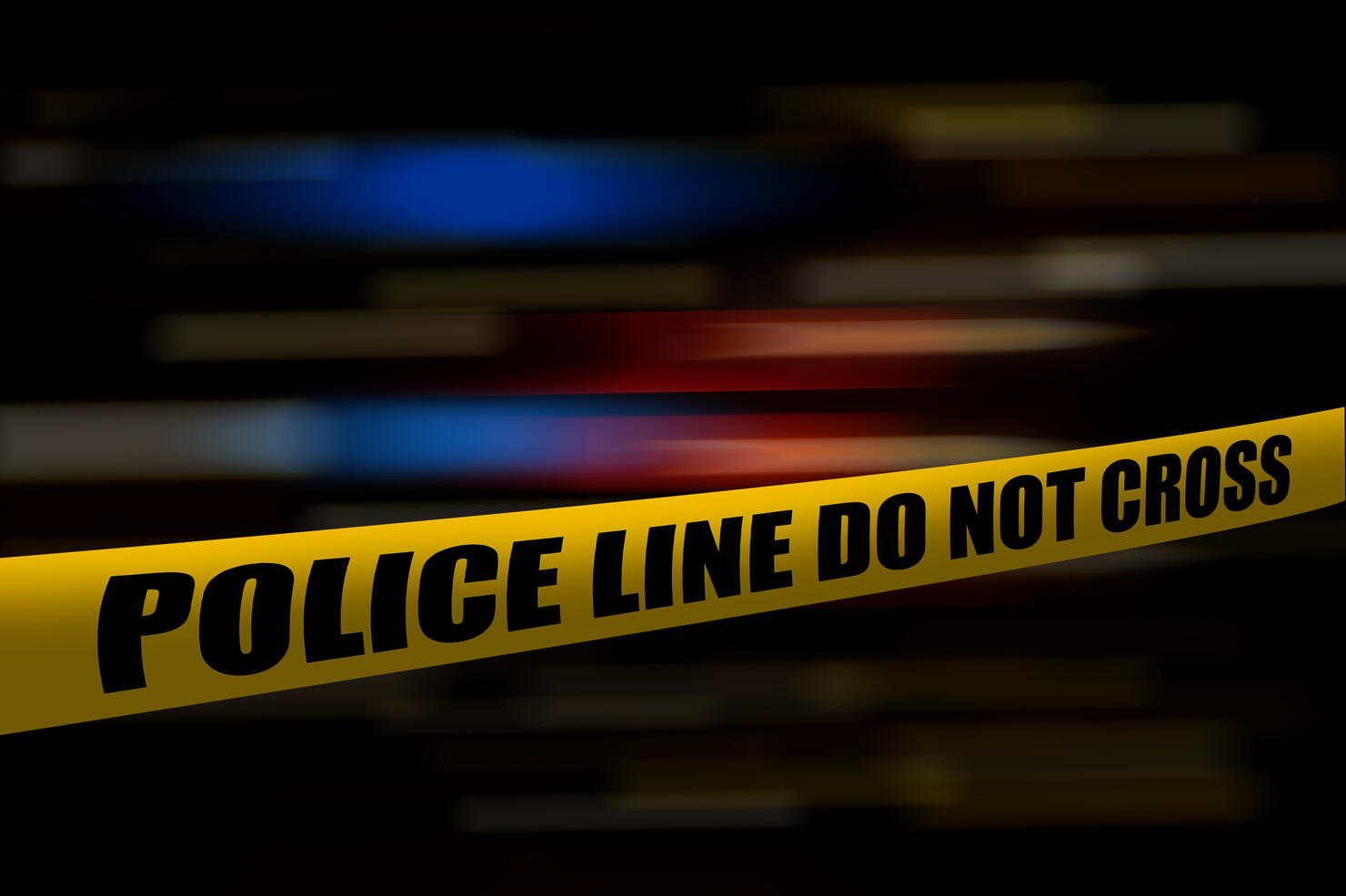 Yellow police tape at night with blurred blue and red lights from police cars and emergency vehicles.