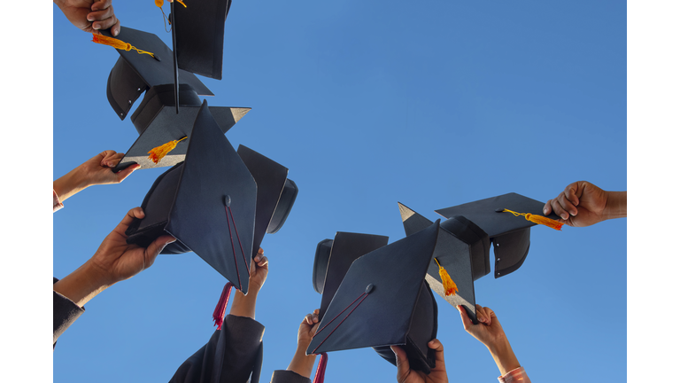 The students holding a shot of graduation cap by their hand in a bright sky during ceremony success graduates at the University, Concept of Successful Education in Hight School,Congratulated Degree