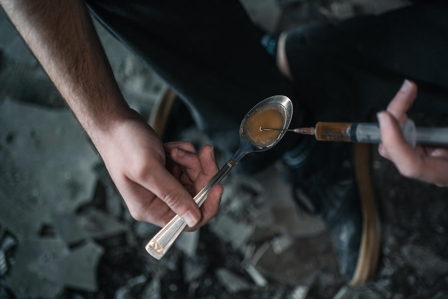 Drug addict using syringe preparing drug in spoon for shooting up