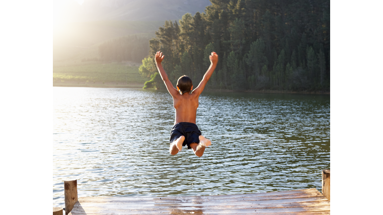 Young boy jumping into lake