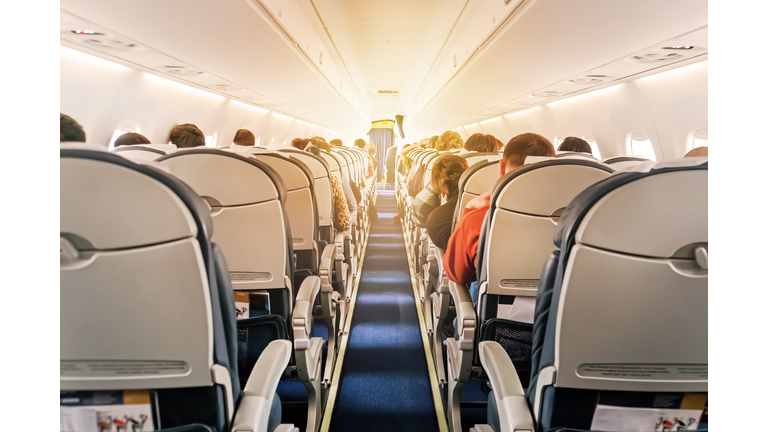 Commercial aircraft cabin with rows of seats down the aisle