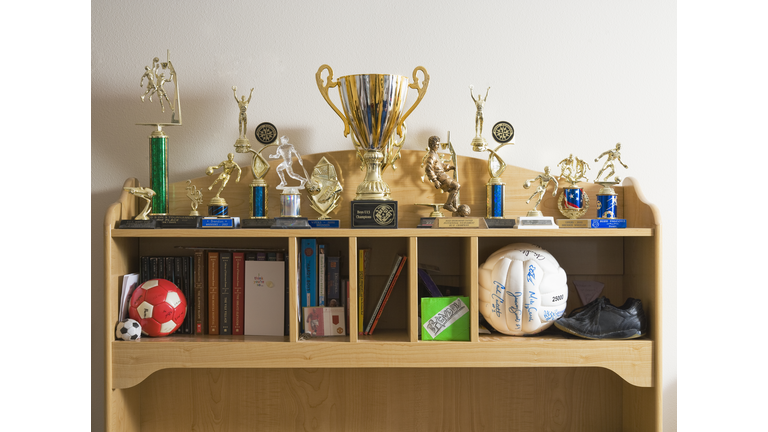 Sports trophies, balls and books on shelves
