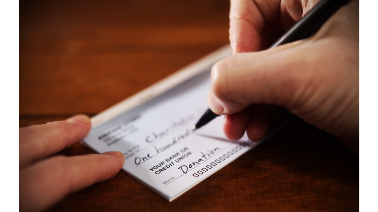 Close up View of Hand Writing A Donation Check