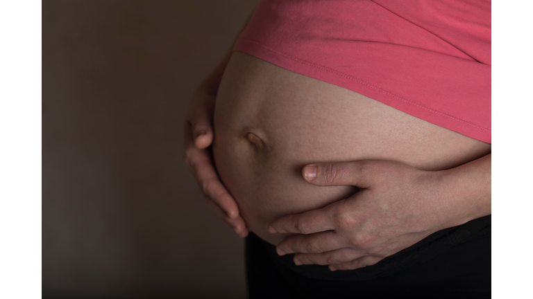 Young pregnant between 30 and 35 years old woman touches her belly.