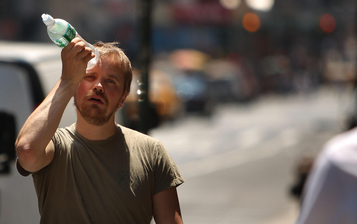 Man cools himself with a bottle of water.