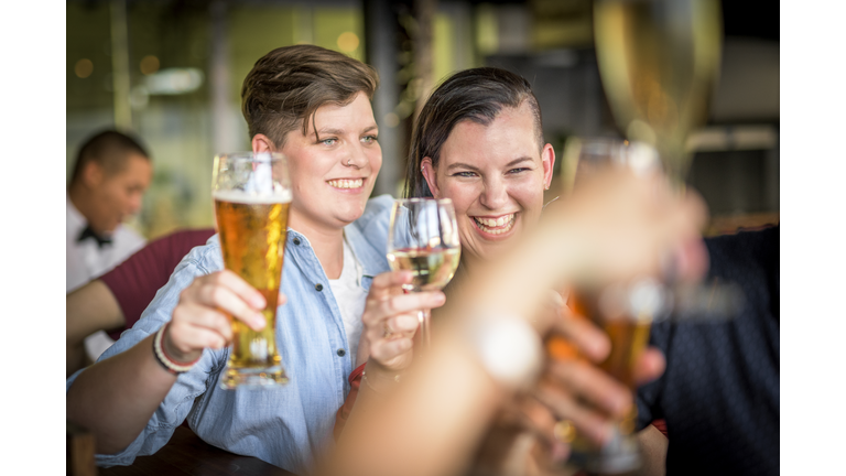 Happy lesbian couple enjoying alcoholic drinks st bar.