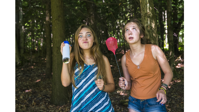 Teen girls make faces chasing insects in a forest