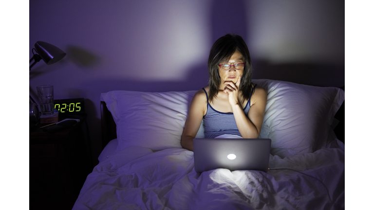 Woman working late on laptop in bed