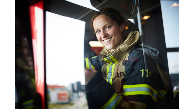 Portrait of smiling female firefighter sitting in fire engine