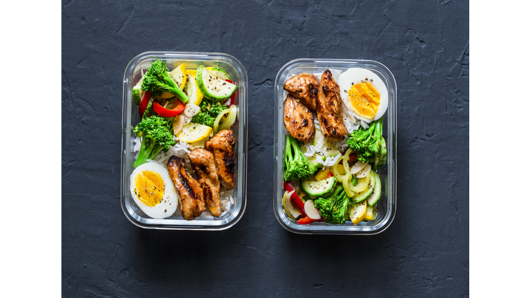 Rice, stewed vegetables, egg, teriyaki chicken - healthy balanced lunch box on a dark background, top view. Home food for office concept