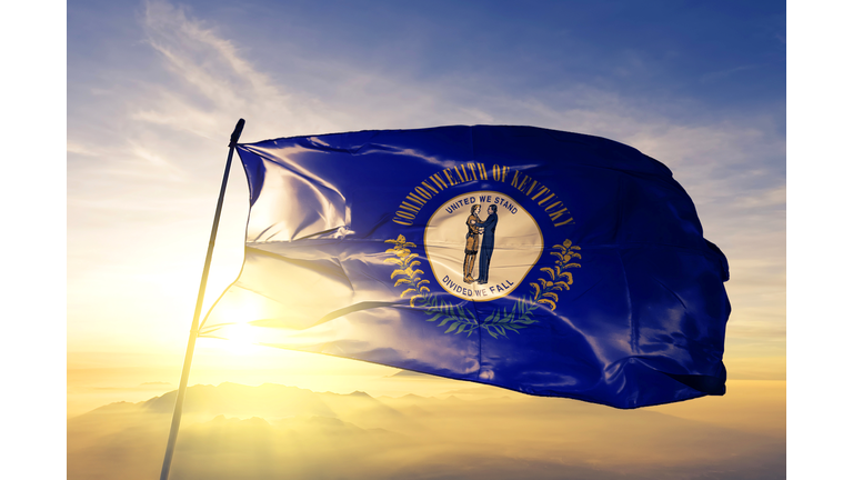 Kentucky state of United States flag textile cloth fabric waving on the top sunrise mist fog