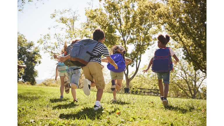 Five school kids running in a field, back view, close up